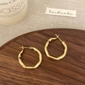 Macro detail of gold irregular geometric earrings on a wooden tray with warm lighting - Gold