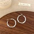 Detailed view of polished silver irregular geometric earrings on a wooden tray - Silver
