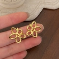Detalle de pendientes de flores huecas doradas que muestran el diseño floral pulido - Dorado