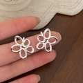 Detalle de los pendientes de flores huecas plateadas con un diseño pulido minimalista - Plateado