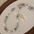 Dettaglio di una collana di perle grigie e bianche su un supporto espositivo di lusso - Collana di Perle Bianche e Grigie