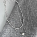 Dettaglio di collana a doppio strato con scaglie di metallo argento e pendente con perla lucida - Collana Con Perle Argentate
