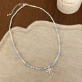 Close-up of beaded necklace with light blue stones and hollow bow pendant on wood surface - Sky Blue Necklace