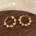 Detalle de pendientes de aro dorados con textura espiral sobre bandeja de madera - Dorado