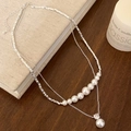 Detail of double-layer silver necklace with gradient pearls and sparkling zircon pendant - White