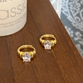 Détail de boucles d'oreilles créoles dorées vintage avec zircon ovale et texture rainurée - Doré