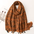 Dettaglio di sciarpa paisley arancione bruciato con nappe bicolori e motivi etnici boho - Caramello