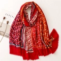 Close-up of vibrant red linen-feel scarf with gold foil accents and tassel edges - Red