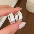 Detail van handgehouden zilveren oorringen met een matte geborstelde afwerking - Zilveren geborstelde oorbellen / Zilver