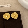 Detail of wavy gold earrings with concentric circular textures on a jewelry stand - Gold
