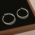 Silver double hoop earrings with a layered twist design on a black velvet display - Double Loop Cross Geometric Design (A-1205) / Silver