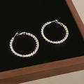 Macro shot of silver twisted hoop earrings with a metallic finish on a black mirror surface - Braided Woven Texture (A-1180) / Silver