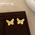 Close-up of golden butterfly stud earrings with pearl tassel on a dark velvet display - Matte Gold Butterfly Stud Earrings