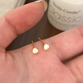 Gros plan de petites boucles d'oreilles en émail tenues en main pour les détails - Blanc