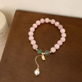 Pink natural stone beaded bracelet with green accents and a pearl charm on a wooden surface - Pink Single-Layer Bracelet