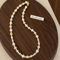 Detailed shot of handmade mixed color pearl necklace on a rustic wooden tray - Gold Mixed Pearl Necklace
