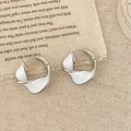 Macro-opname van zilveren Mobius oorbellen met wit emaille op vintage linnen stof - Wit