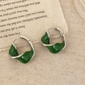 Detail of silver twisted hoop earrings with dark green enamel on rustic linen backdrop - Green