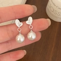 Détail des boucles d'oreilles perles et feuilles argentées tenues à la main - Style Perle Feuille d'Argent