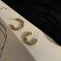 Dettaglio macro di orecchini a C dorati con texture effetto lava in argento frantumato - Oro
