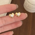 Eleganti orecchini a lobo a cuore in oro con perla bianca tenuti in mano - Oro