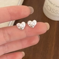 Dettaglio orecchino a lobo a cuore con perla e trama artigianale indossato sul lobo - Argento