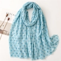 Close-up of light blue cotton-linen scarf with geometric gold patterns and fringe edges - Blue