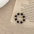 Détail de bague perlée avec perles argentées et noires sur fond en lin texturé vintage - Bague en Perles d'Imitation Noires