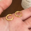 Nahaufnahme der goldenen Creolen mit gebürsteter Textur zur Darstellung von Maßstab und Detail - Gold