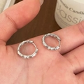 Silberne Creolen im Bambus-Design gehalten in der Hand vor gemütlichem Holz-Hintergrund - Bambus Gelenk Hoop Stil / Silber