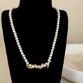 Luxury pearl necklace with golden snake pendant and green gemstone on a velvet stand - Gold