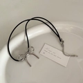 Close-up of a silver bow pendant necklace with a black cord on a white tray - Bowknot Black Cord Chain / Black (Cord Style)