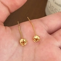 Detailed macro view of gold twist knot tassel earrings held in hand for close inspection - Gold Knot Tassel Stud Earrings / Gold