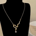 Dettaglio ravvicinato di una collana a serpente dorata con zirconi su un busto nero - Collana Oro