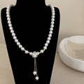 Dettaglio della collana di perle bianche con pendente a fiore e nappe dorate - Stile Perla di Qualità Superiore