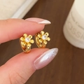 Orecchini a cerchio a forma di fiore dorati con zirconi su uno sfondo in legno caldo - Oro