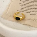Dettaglio di un anello vintage dorato con opale nero ovale e fascia larga regolabile - Agata nera dorata