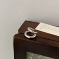 Detail view of a silver double-layered crisscross ring on a wooden jewelry display box - Silver