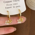 Detail van gouden bloemenoorbellen met zirkonia en vakmanschap van 100% koper - Goud