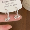 Detailopname van verzilverde bloemenoorbellen met zirkonia kwastjes op een koperen basis - Zilver