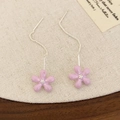 Detail of pink floral tassel earrings with long silver chains on a rustic wood surface - Drip Oil Purple