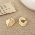 Detail van crème beige gedraaide C-vormige oorbellen op rustieke linnen achtergrond - Broken Wit