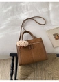 Detail of brown suede tote with metal zipper pocket and cute plush charm on a chair - Brown with Pendant