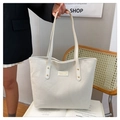 Detail of white corduroy tote bag featuring vertical texture and leather brand patch - White