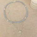 Double-layer necklace with blue beads and silver bow pendant on natural linen background - Light Blue Natural Stone Style