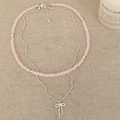 Detail of pink beaded double layer necklace with a silver bow pendant on linen - Pink Natural Stone Style