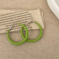 Detail van felgroene hars oorringen op een artistieke achtergrond van linnen en keramiek - Groen