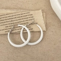 Detail van minimalistische witte hars oorringen op een vintage stoffen achtergrond - Wit