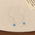 Detailopname van zilveren kettingoorbellen met lichtblauwe druppelhangers op stof - Meerblauw