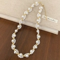 Elegante collana di perle fatta a mano con perle dorate e chiusura su sfondo di legno - Collana di perle elegante